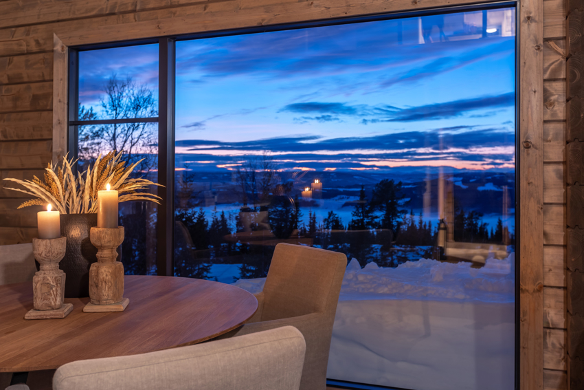 Interiør — spiseplass med panoramavinduer mot kveldshimmel